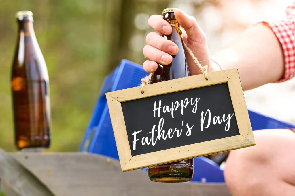 Father's Day sign hanging from a beer bottle held by hand outdoors