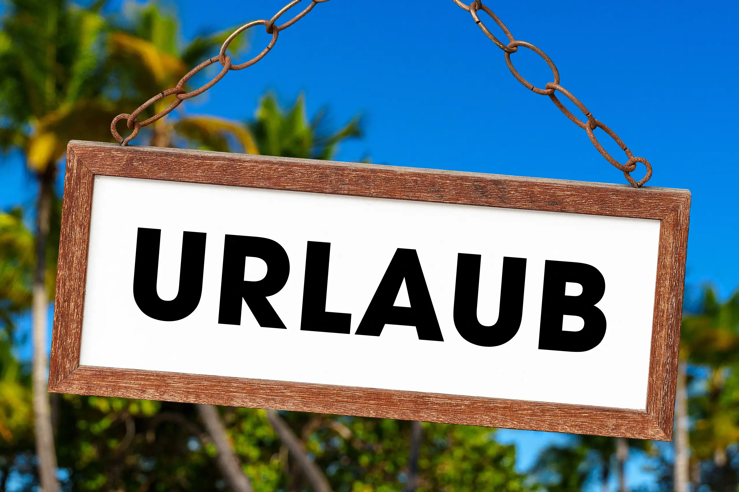 Urlaub Bild mit großem Schild vor tropischen Palmen und blauem Himmel