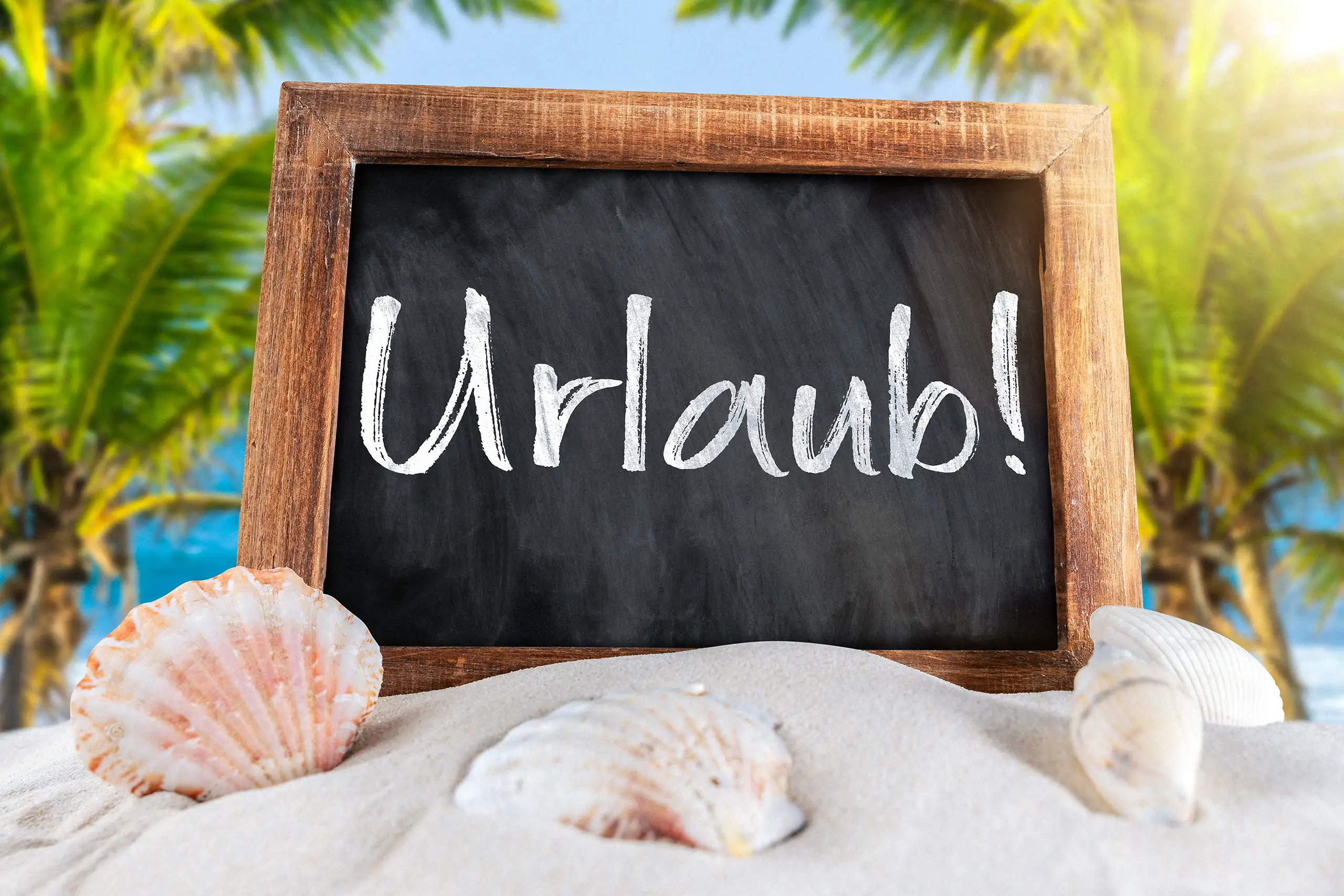 Urlaub Bild mit schwarzer Kreidetafel, Schriftzug Urlaub, Muscheln, Sand, Palmen und Meer