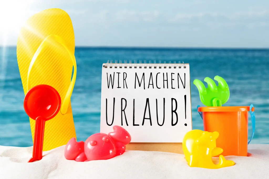 wir machen urlaub bild mit notizblock, flip-flops, strandspielzeug, sand und blauem meer